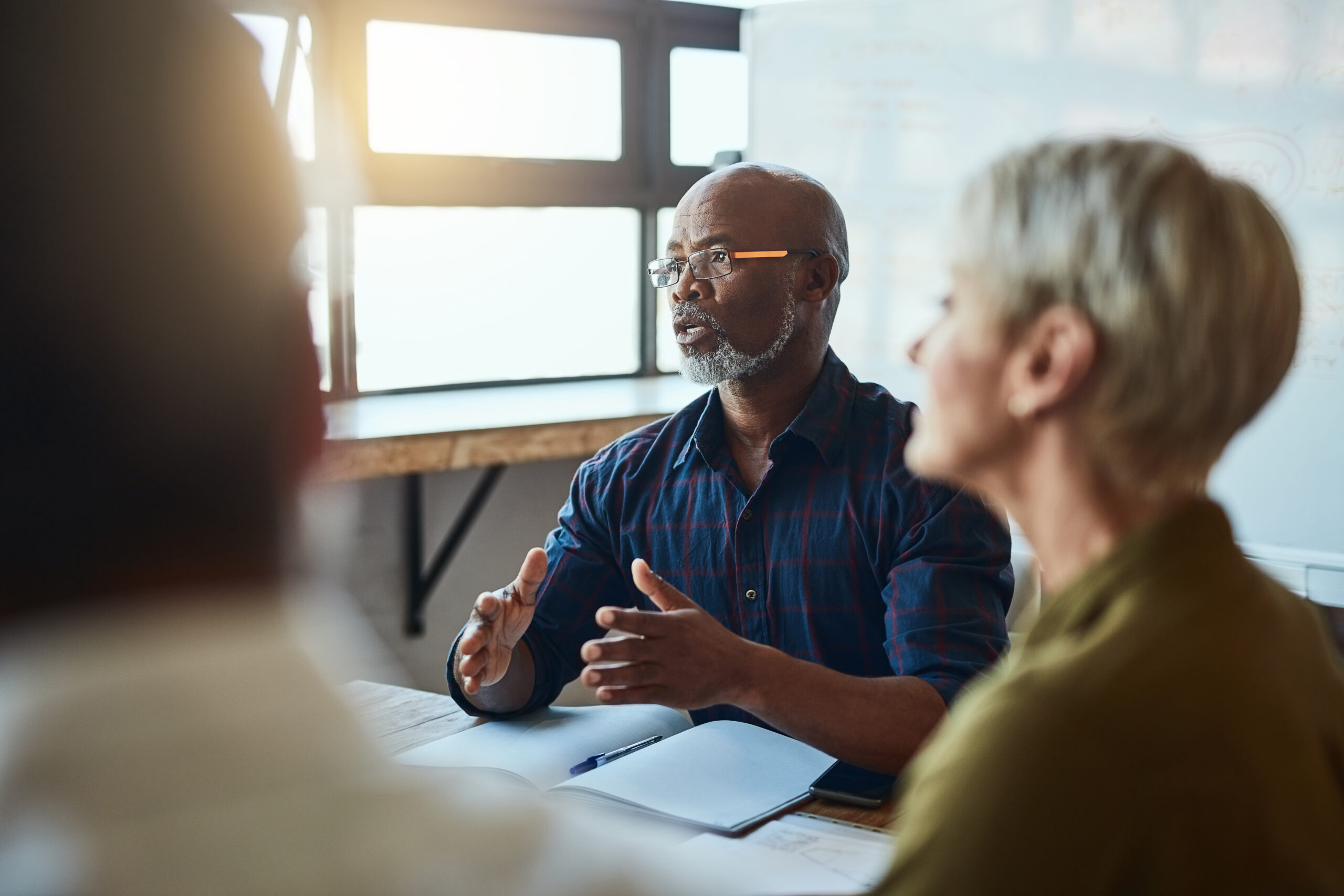 Business people, meeting and leadership of black man in office, talking or speaking. Teamwork, ceo and senior African male professional brainstorming, collaboration or planning strategy in workplace